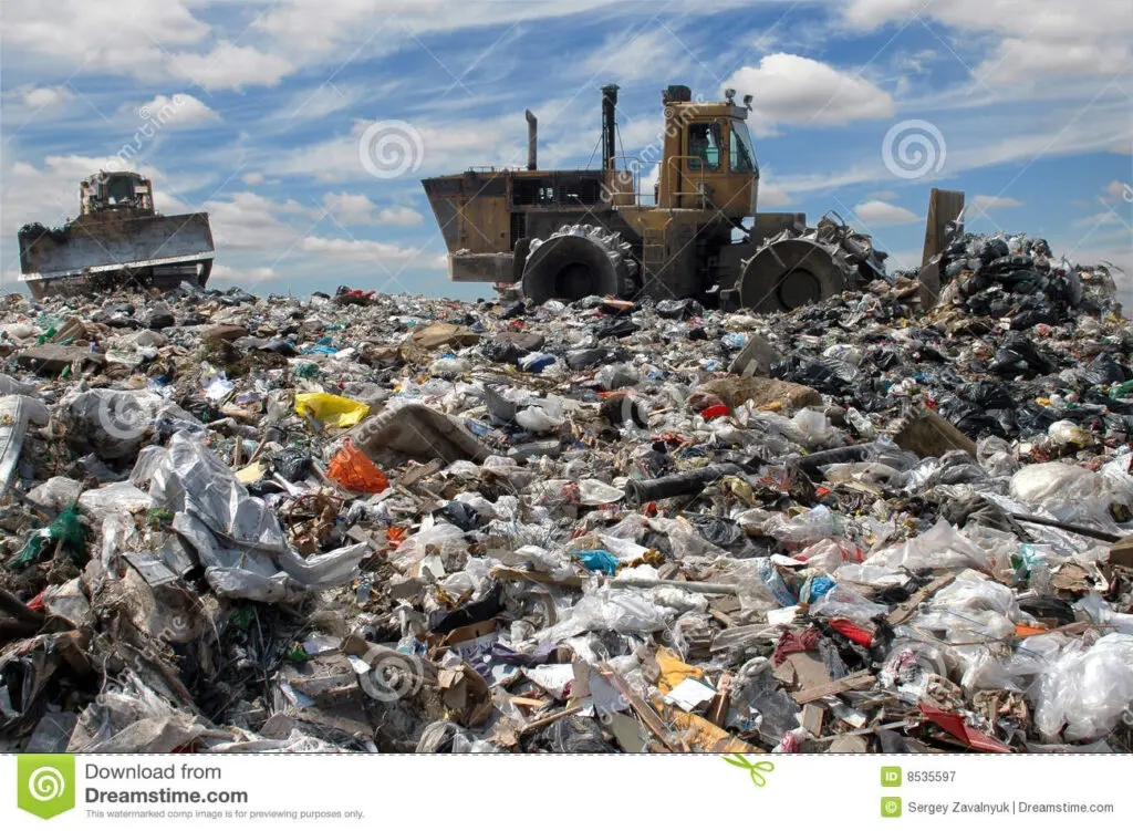 A dump truck is in the middle of a pile of trash.